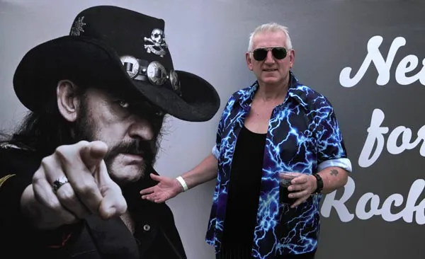 Rob standing next to a billboard of Lemmy Kilmister
